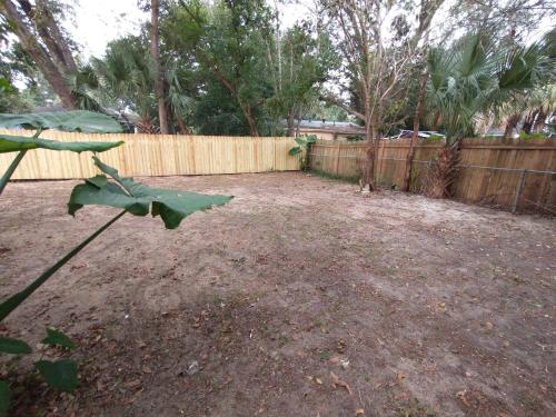 a backyard with a wooden fence and a dirt yard at Welcome to Pineapple House! in Pensacola