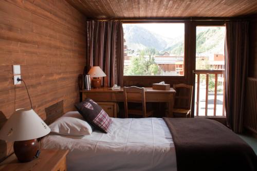 een slaapkamer met een bed, een bureau en een raam bij Les Crêtes Blanches in Val dʼIsère