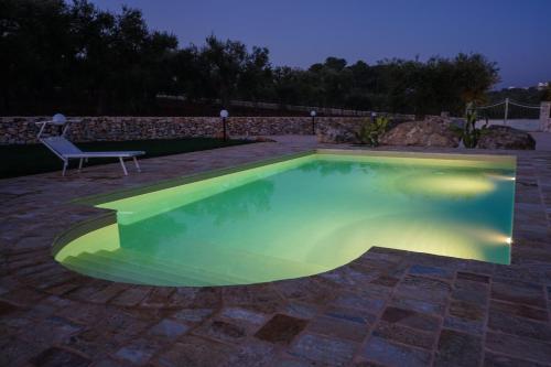 a swimming pool at night with a bench next to it at Quattroperle Trulli - Relax - Puglia in Castellana Grotte