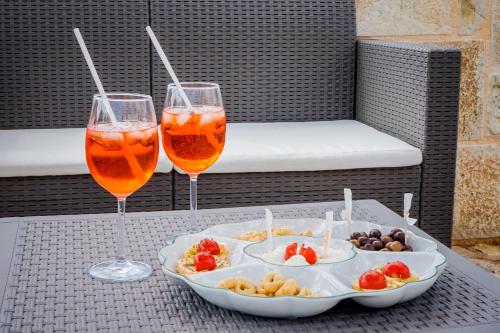 two glasses of wine and a tray of food on a table at Quattroperle Trulli - Relax - Puglia in Castellana Grotte