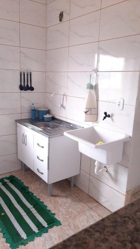a white bathroom with a sink and a stove at 3º andar independente - Casa a 50m da praia com vista lateral para o mar in Saquarema