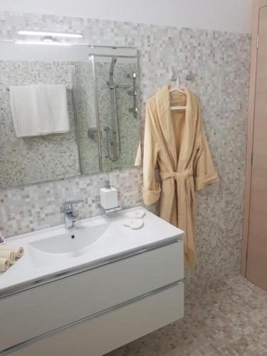 a bathroom with a sink and a robe on a mirror at De Luxe Apartments Eden in Sirmione