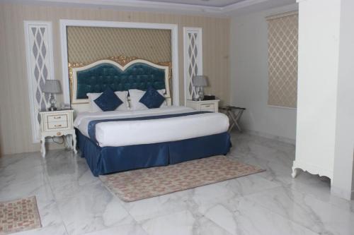 a bedroom with a large bed with a blue headboard at jawharat alshlal Establishment in Hafr Al Baten