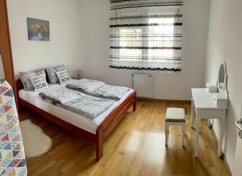 um quarto com uma cama, uma secretária e uma janela em Paris apartment -Free private parking em Novi Sad