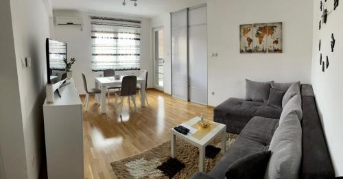 uma sala de estar com um sofá e uma mesa em Paris apartment -Free private parking em Novi Sad