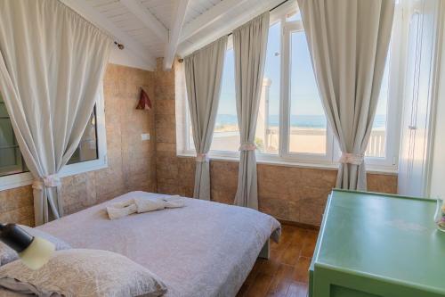 a bedroom with a bed and windows with a view of the ocean at Beach Villa Athanasia - villa with private pool on the beach by PosarelliVillas in Acharavi