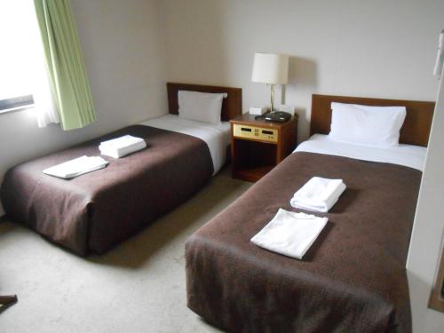 two beds in a hotel room with towels on them at Select Inn Mishima in Mishima