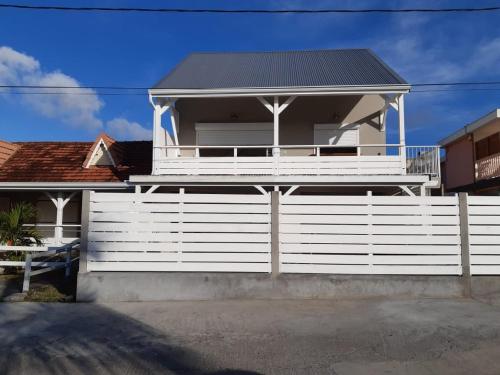a white fence in front of a house at Appartement neuf a 150 metres de la mer wifi in Le Diamant