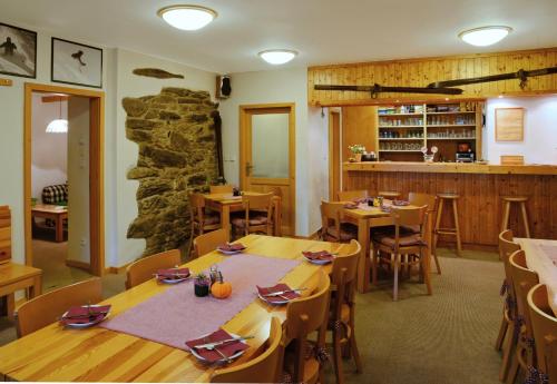 a restaurant with wooden tables and chairs and a stone wall at Penzion Apalucha in Dolní Malá Úpa