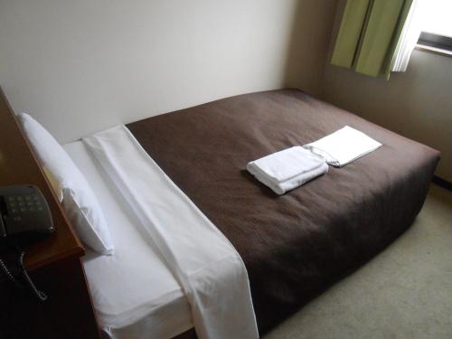 a bedroom with a bed with two towels on it at Select Inn Mishima in Mishima