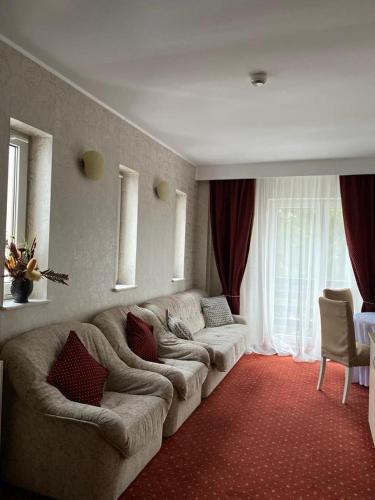 a living room with a large couch in a room at Hotel Miraj - Restaurant & Sauna & Biliard in Poiana Brasov