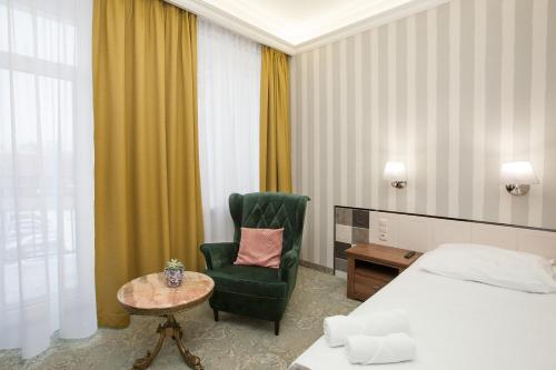 a hotel room with a bed and a chair and a table at Kamienica Boutique ApartHotel in Białystok