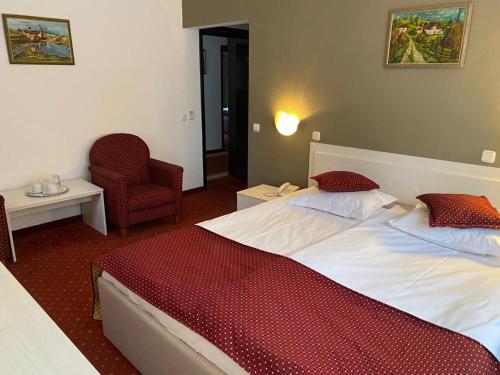 a hotel room with two beds and a chair at Hotel Miraj - Restaurant & Sauna & Biliard in Poiana Brasov