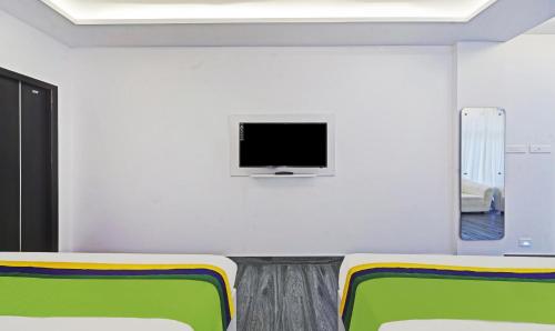 a room with two chairs and a tv on a wall at Treebo Premium Raffis' Andalusia Bay Way in Puducherry