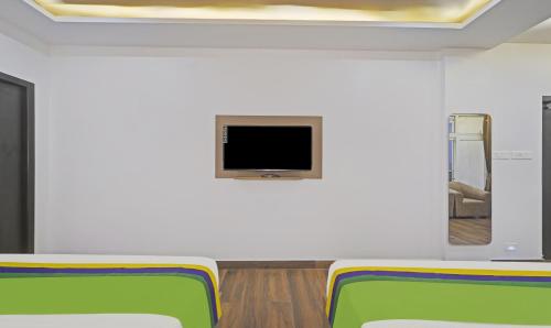a room with two chairs and a tv on a wall at Treebo Premium Raffis' Andalusia Bay Way in Puducherry