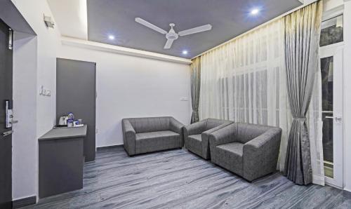 a living room with two chairs and a ceiling fan at Treebo Premium Raffis' Andalusia Bay Way in Puducherry