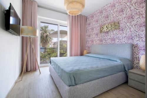 a bedroom with a blue bed and pink wallpaper at Italianway - Cristoforo Colombo 12 in San Bartolomeo al Mare