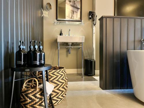 a bathroom with a sink and a table with bottles on it at Van der Gang Suites uniek design in hartje Dokkum in Dokkum