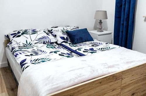a bed with blue and white pillows on it at Apartament Boryna in Łomża