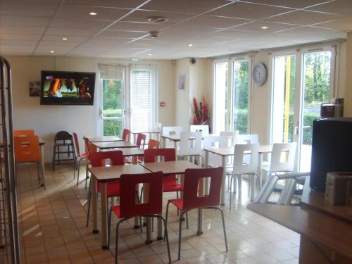 une salle à manger avec des tables et des chaises blanches dans l'établissement Premiere Classe Dunkerque Loon Plage, à Loon-Plage