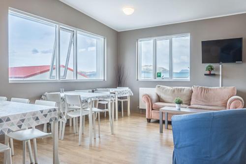 una sala da pranzo con tavoli, sedie e finestre di Stöð Guesthouse and apartments a Grundarfjordur