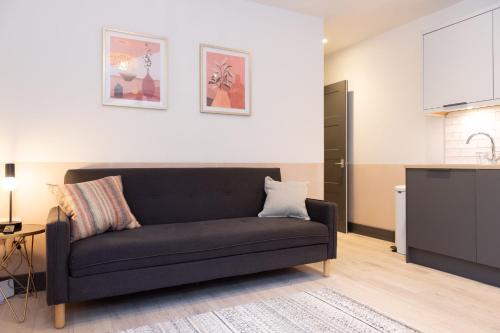 a living room with a black couch in a kitchen at 1 Castle Mews in Salisbury
