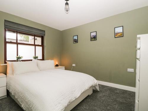 um quarto com uma cama branca e paredes verdes em Andra Ghyll em Keswick