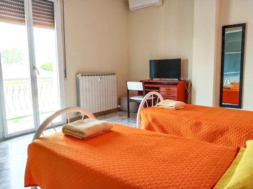 a room with two beds with orange sheets and a television at Casa Bignardi - Affitti Brevi Italia in Modena