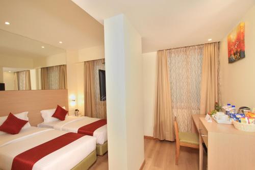 Habitación de hotel con 2 camas y escritorio en La Sara Regent, en Bangalore