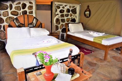 a room with two beds and a table with flowers at ELANGATA OLERAI LUXURY TENTED CAMP in Narok