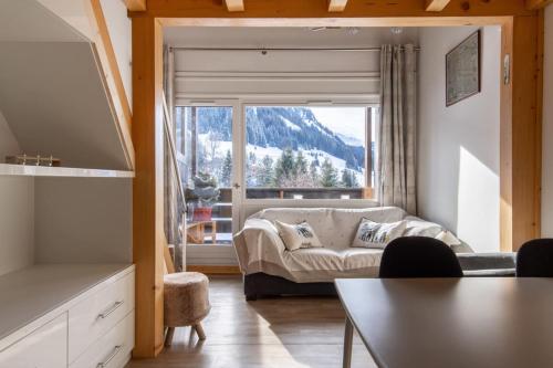 uma sala de estar com um sofá e uma grande janela em Comfortable studio with terrace and mountain views em Megève