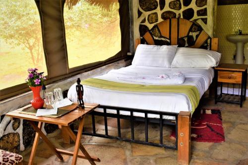 a bedroom with a large bed and a table at ELANGATA OLERAI LUXURY TENTED CAMP in Narok