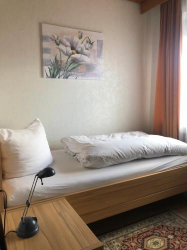 a bed with white sheets and a lamp in a room at Gasthof Rose in Reutlingen