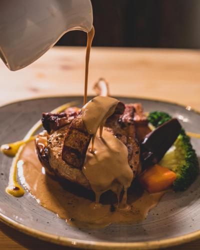 a plate of food with gravy on it with broccoli at The Red Lion at Hellidon in Daventry