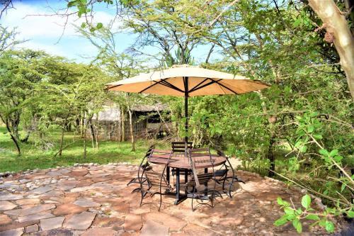 a table and chairs under an umbrella on a stone patio at ELANGATA OLERAI LUXURY TENTED CAMP in Narok