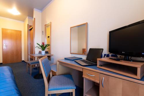 a hotel room with a television and a desk with a laptop at Tamaris Rooms in Zadar