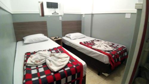 two beds in a room with red and white blankets at HOTEL PAULISTANO Terminal Tietê in Sao Paulo