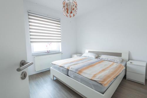 a white bedroom with a bed and a window at Zentral gelegene Wohnung in Hannover