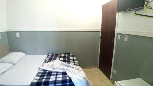 a small bedroom with a bed with a checked blanket at HOTEL PAULISTANO Terminal Tietê in Sao Paulo