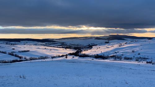a snow covered field with the sun setting in the distance at Viktoria House in Odorheiu Secuiesc