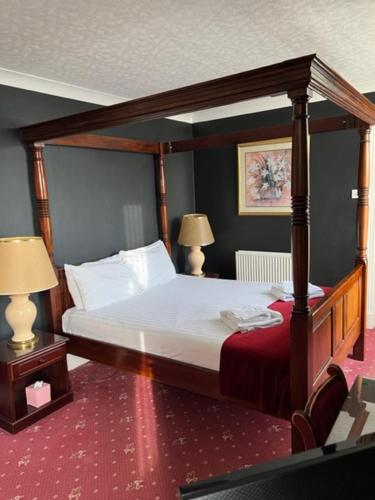a bedroom with a canopy bed and two lamps at Caledonian Hotel in Dumfries
