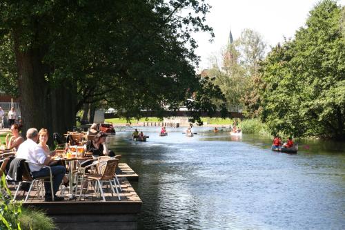 a group of people sitting at tables next to a river at Villa Søholt - Silkeborg Bed and Breakfast in Silkeborg