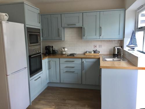 a kitchen with blue cabinets and a white refrigerator at The Olives in Holt