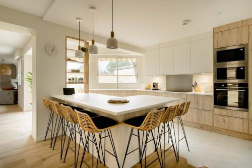 - une cuisine avec une table et des chaises blanches dans l'établissement La Villa l'Escale, somptueuse maison contemporaine, à Angoulême