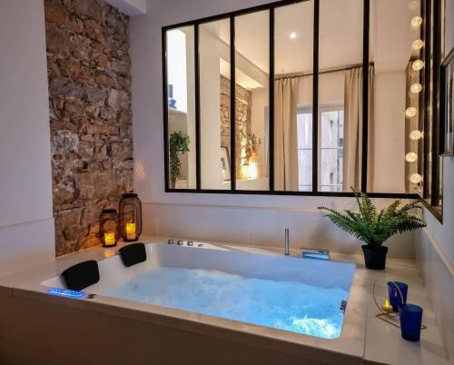La salle de bains est pourvue d'une grande baignoire et d'une grande fenêtre. dans l'établissement Le Capucin - Balnéo - Lyon Centre - Majord'Home, à Lyon