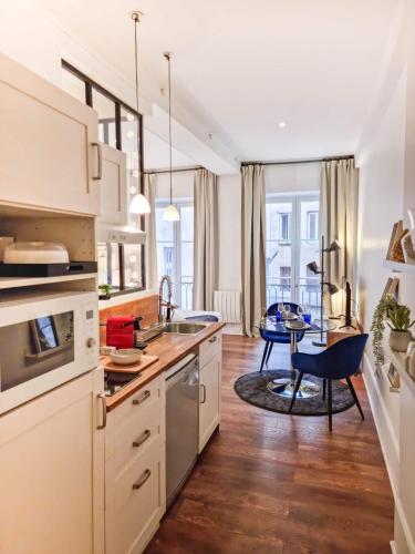 une cuisine avec des placards blancs et une table avec une chaise dans l'établissement Le Capucin - Balnéo - Lyon Centre - Majord'Home, à Lyon