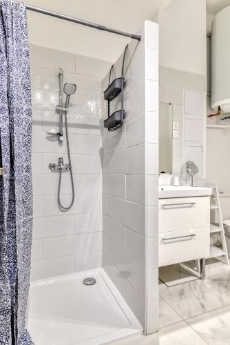 une salle de bain blanche avec une douche et un lavabo dans l'établissement Loft Plage du Grazel, à Gruissan