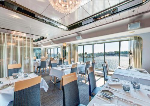 um restaurante com mesas e cadeiras brancas e uma grande janela em Viking Line ferry Gabriella - Cruise Helsinki-Stockholm-Helsinki em Helsínquia