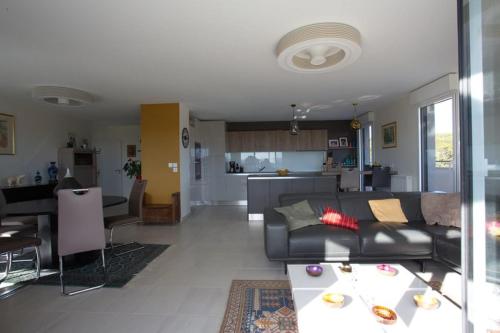 un salon avec un canapé noir et une cuisine dans l'établissement Apt - terrace panoramic view and wifi, à Aix-en-Provence