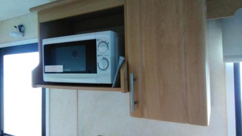 a microwave sitting on top of a cabinet in a kitchen at Family Fun 2-Bed caravan family romney Marsh in Burmarsh